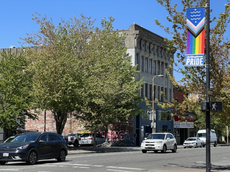 A banner on display in downtown Bellingham as cars drive by.