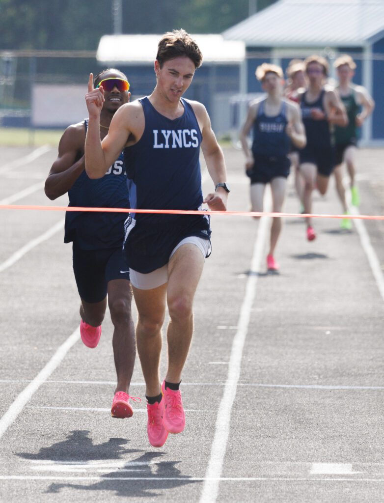 Lynden Christian's Andrew Luce holds up a finger ahead of other runners as he keeps his eyes on the finish line.