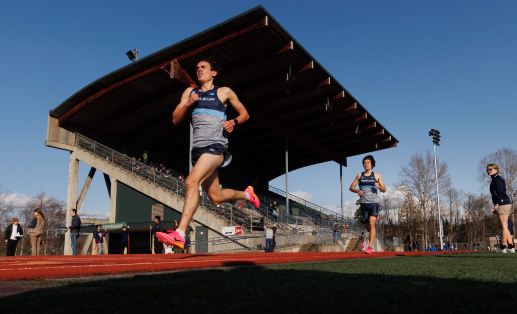 Squalicum's Tyler Nielsen leads teammate Wesley Sluys as spectators watch from the bleachers and sideline.