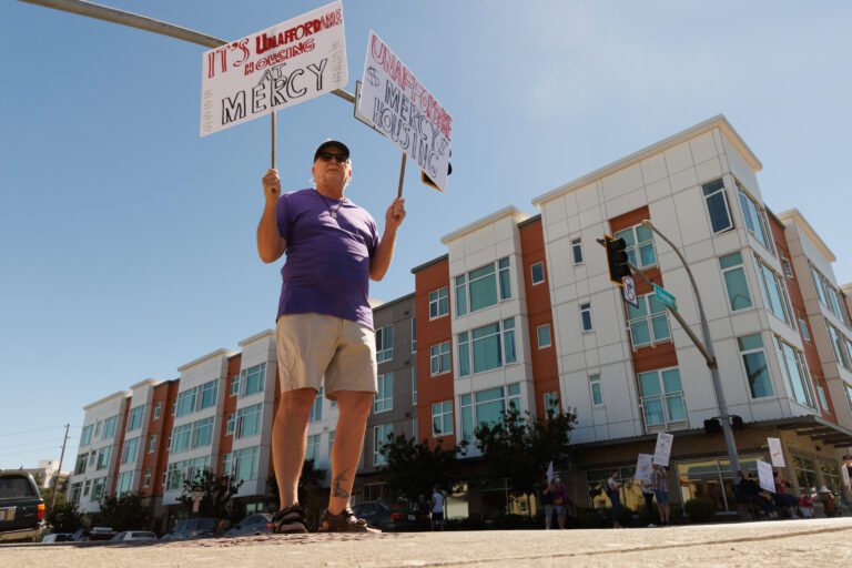 A protestor holds up two signs with both his hands.