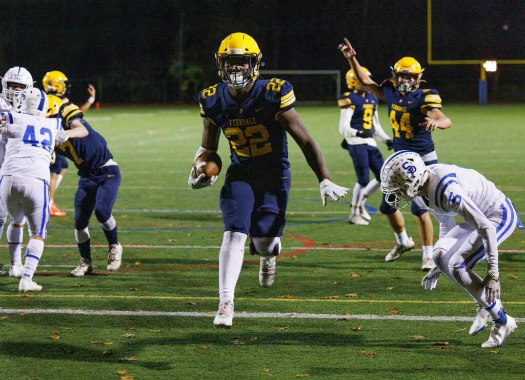 Ferndale’s Isaiah Carlson cruises into the end zone past defenders as a teammate signals behind him.