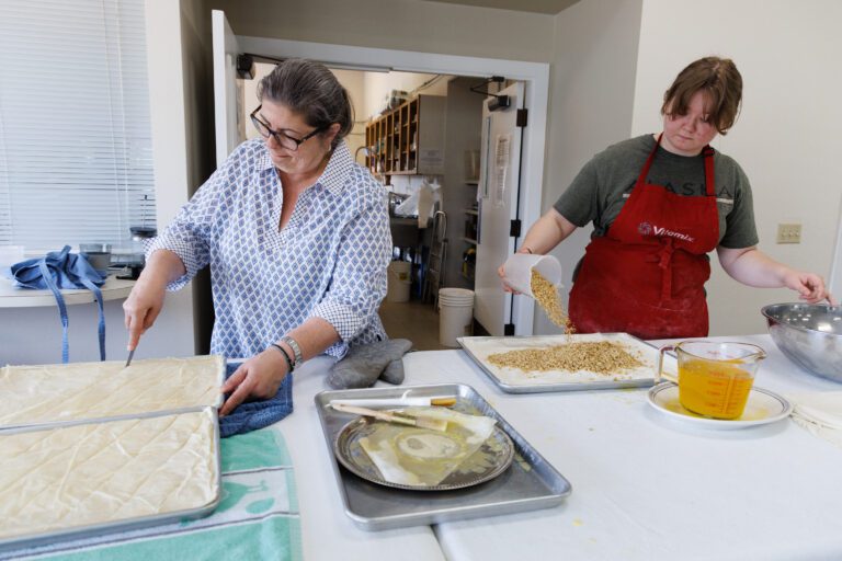 At St. Sophia Greek Orthodox Church, Marie Boulos cuts baklava into servings while Alida Schindler pours nuts over filo dough.