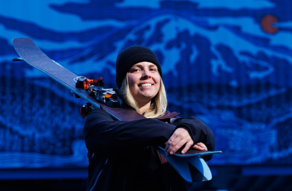 Jasmine Neubauer smiles with her skis on her shoulder.