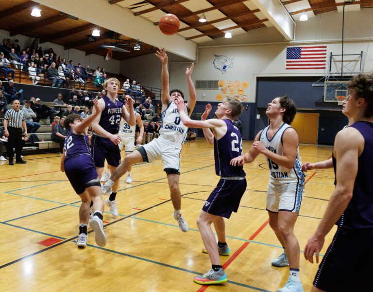 Lynden Christian’s Tyler Sipma makes the basket as he falls backwards while under pressure from defenders.