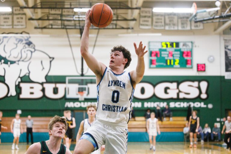 Lynden Christian's Tyler Sipma leaps to score as defenders look up from below.