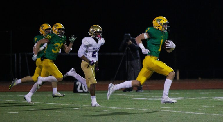 Lynden's Kobe Baar returns an interception for an 81-yard touchdown trailed by a group of players.