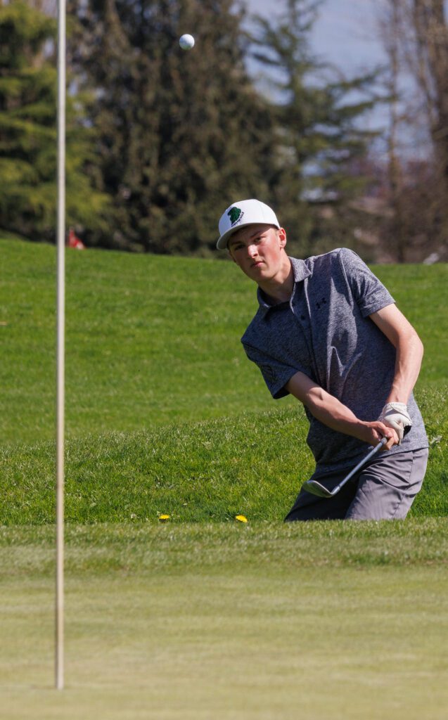 Lynden's Jack Stapleton chips from a deep bunker as the golf ball flies up.