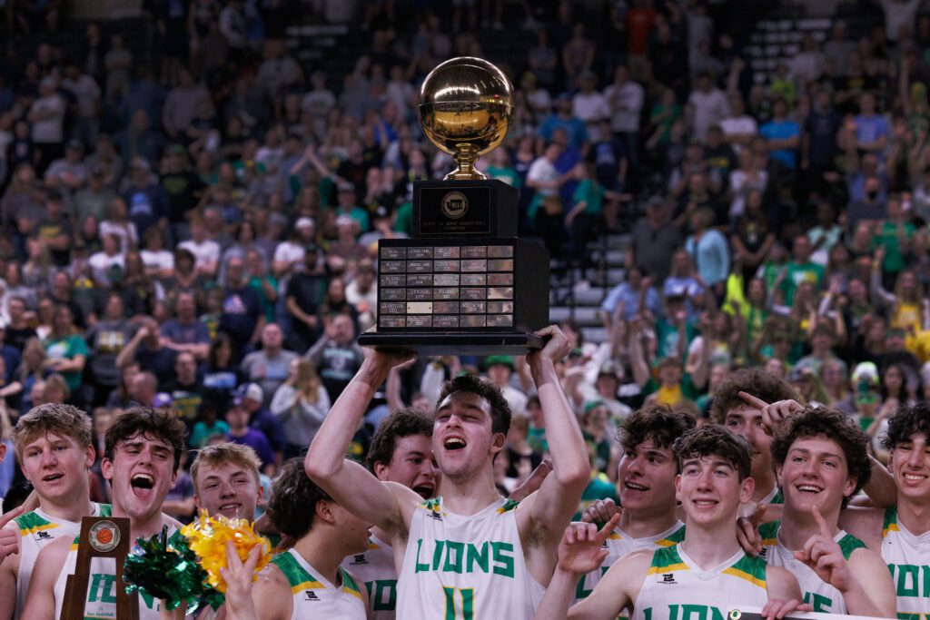 Lynden players celebrate with the championship trophy raised over the team as some members point to the award for the photo.