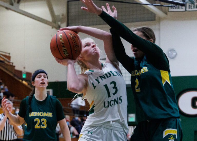 Lynden's Adia Newcomb makes a basket as Sehome's Madi Cooper defends with their arms raised.