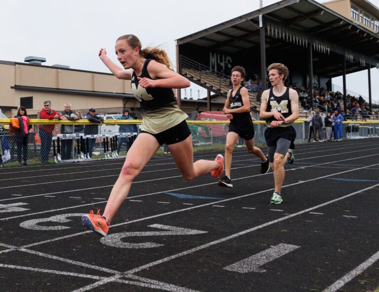 Meridian’s Kayla Aalpoel leans forward and sets a girls school record ahead of competing runners.