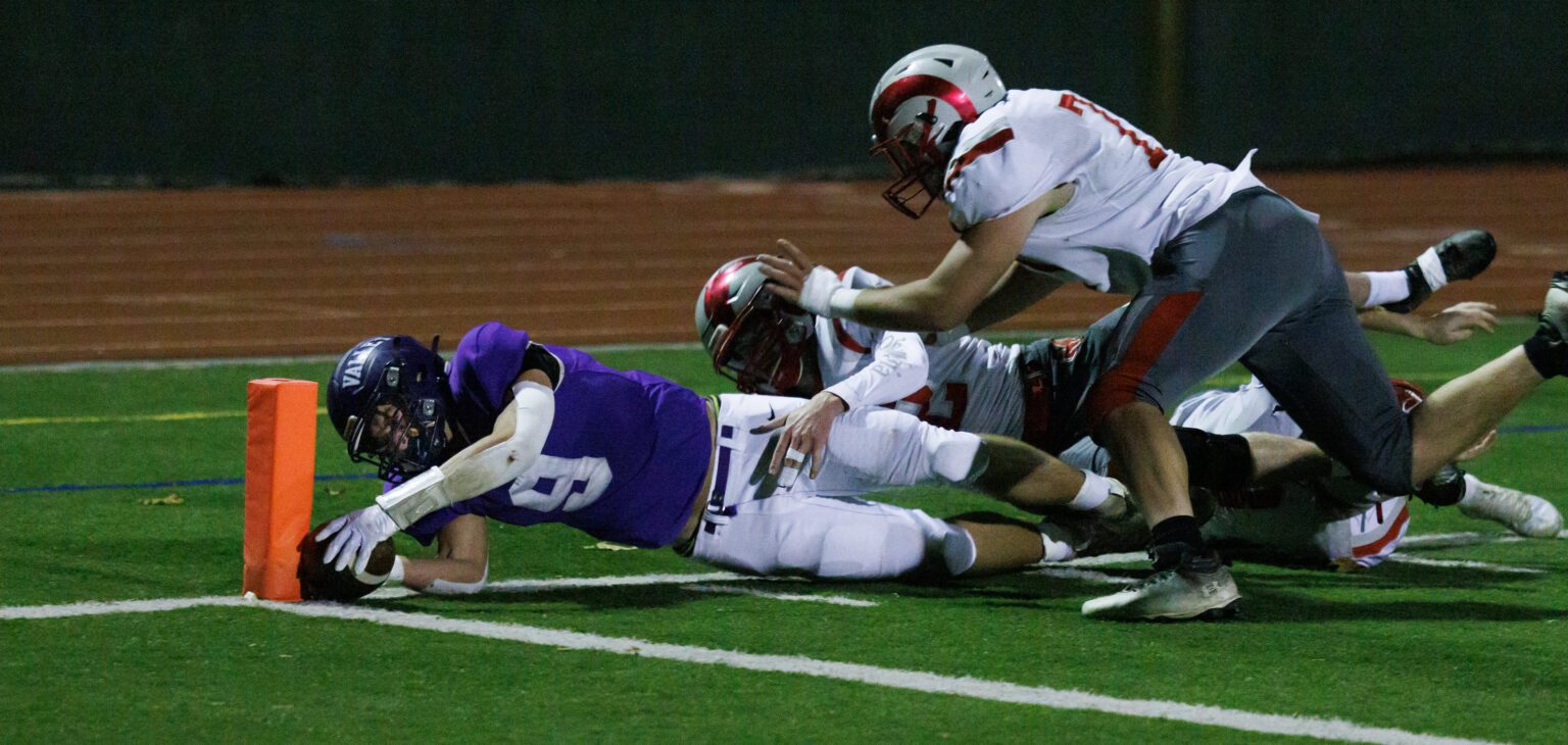 Nooksack Valley’s Colton Lentz reaches for the end zone with a trail of defenders tackling him from behind.