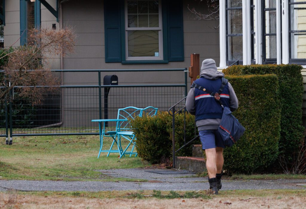 A postal worker walks door-to-door in the Columbia neighborhood delivering mail.