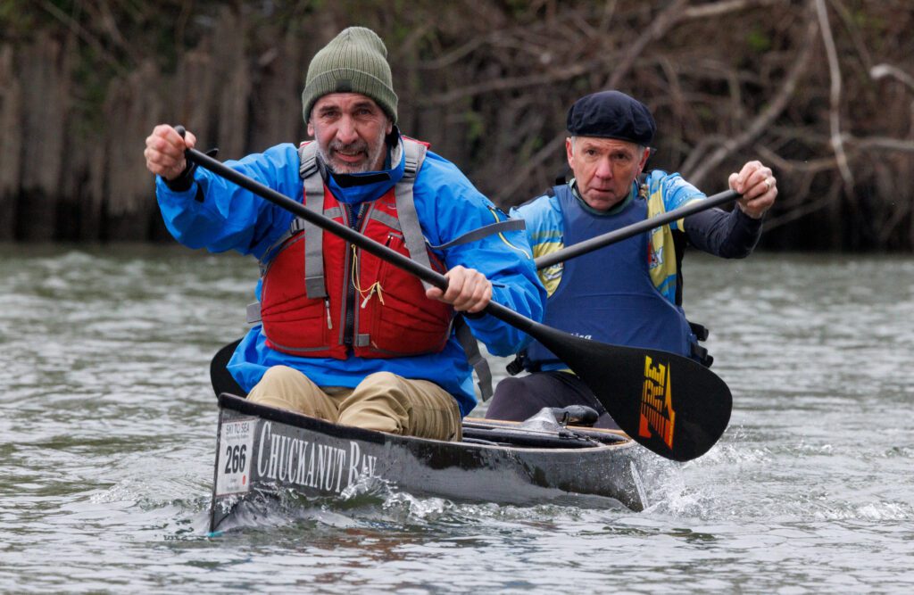 Greg Fosty, left, and Mike Baker, rows with paddles on top of their black kayak.