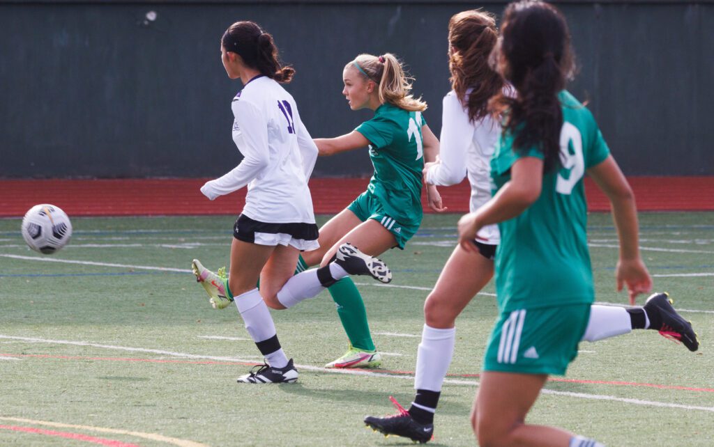 Sehome’s Ryan Boehm, center, kicks the ball while under pressure by two players.