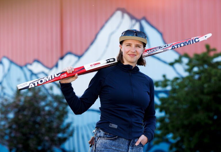 Sydney Papritz poses in front of a Mt Baker mural with a ski on her shoulder.