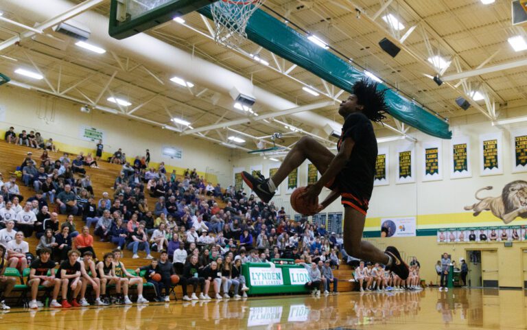 Blaine's Mathew Russ attempts a between-the-legs dunk as a crowd watches from the bleachers.