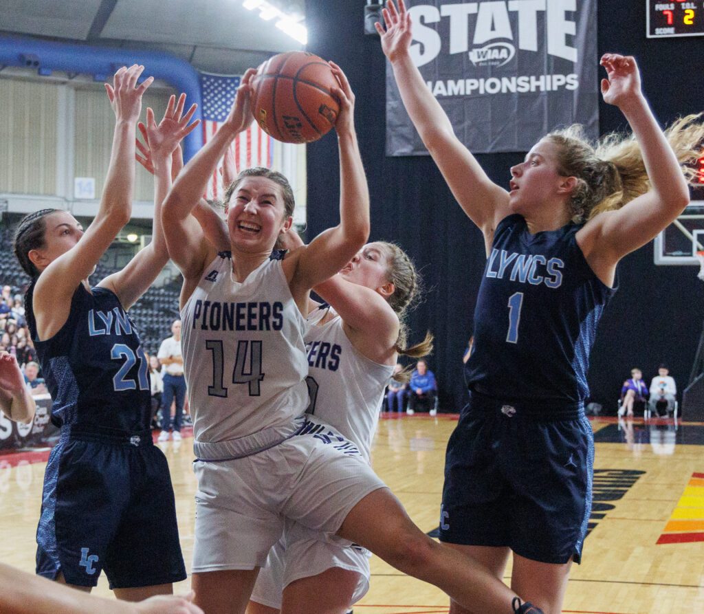 Nooksack Valley’s Devin Coppinger (14) grabs a rebound while under pressure from two defenders and her own teammate behind her.