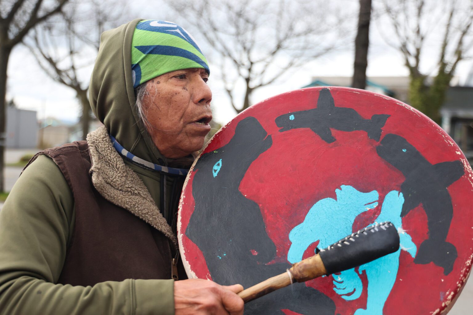 A person drums on the drum Eagle Bear beats that is painted to depict the mothers and daughters of nature in the circle of life.