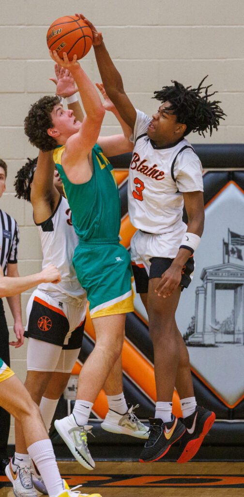 Blaine’s Matt Russ blocks a shot by Lynden’s Trey Smiley mid-air as other players try to reach from behind him.