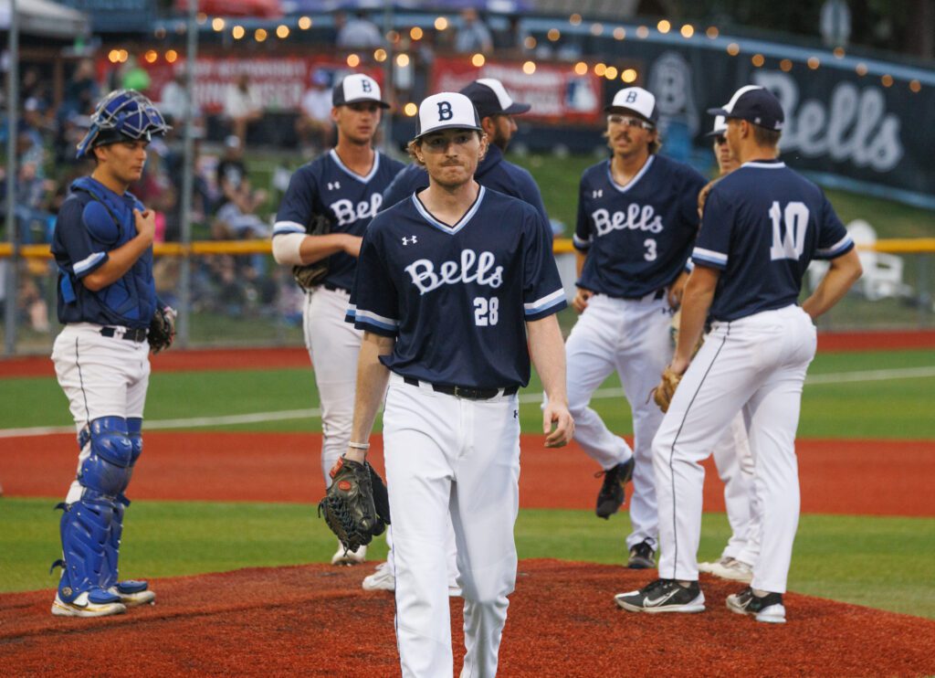 Pitcher Calvin Wood walks to the dugout leaving behind the huddle of players.