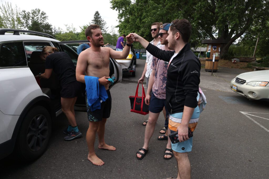 Ethan Hunger gets a fist bump from Paul Freihoefer next to their car and other friends.