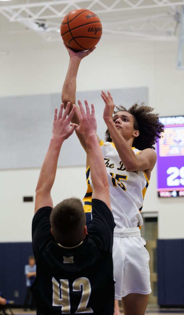 Ferndale's Kevin Woods leaps high for a floater over Meridian's Tyrel Brooks who has both his arms raised in an attempt to block the shot.