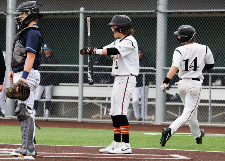 Blaine’s Mason Akre pumps his arms while holding his bat as his teammate walks behind him.