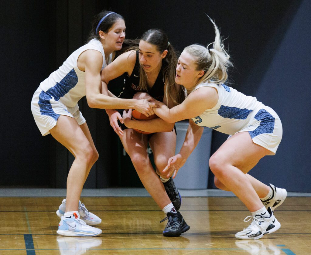 Lynden Christian’s Demi Dykstra and Reganne Arnold try to take the ball from Eastlake’s Darcy McCoy who is trying to drive past both defenders.