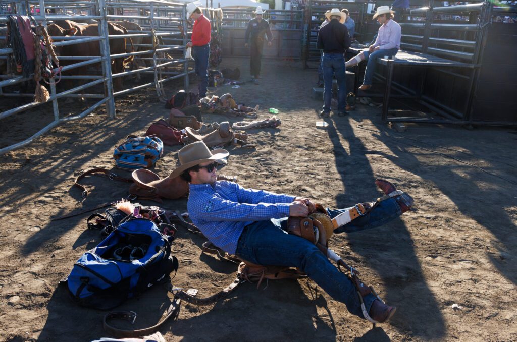 Cameron Messier of Mandaree, N.D., checks the fit of his saddle on the ground.