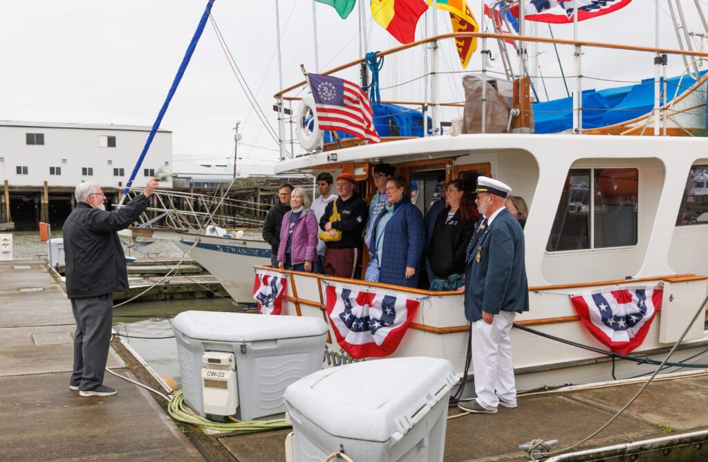 The Rt. Rev. Kevin Bond Allen blesses the Serendipity and its crew and guests as the captain stands to the side of the boat.