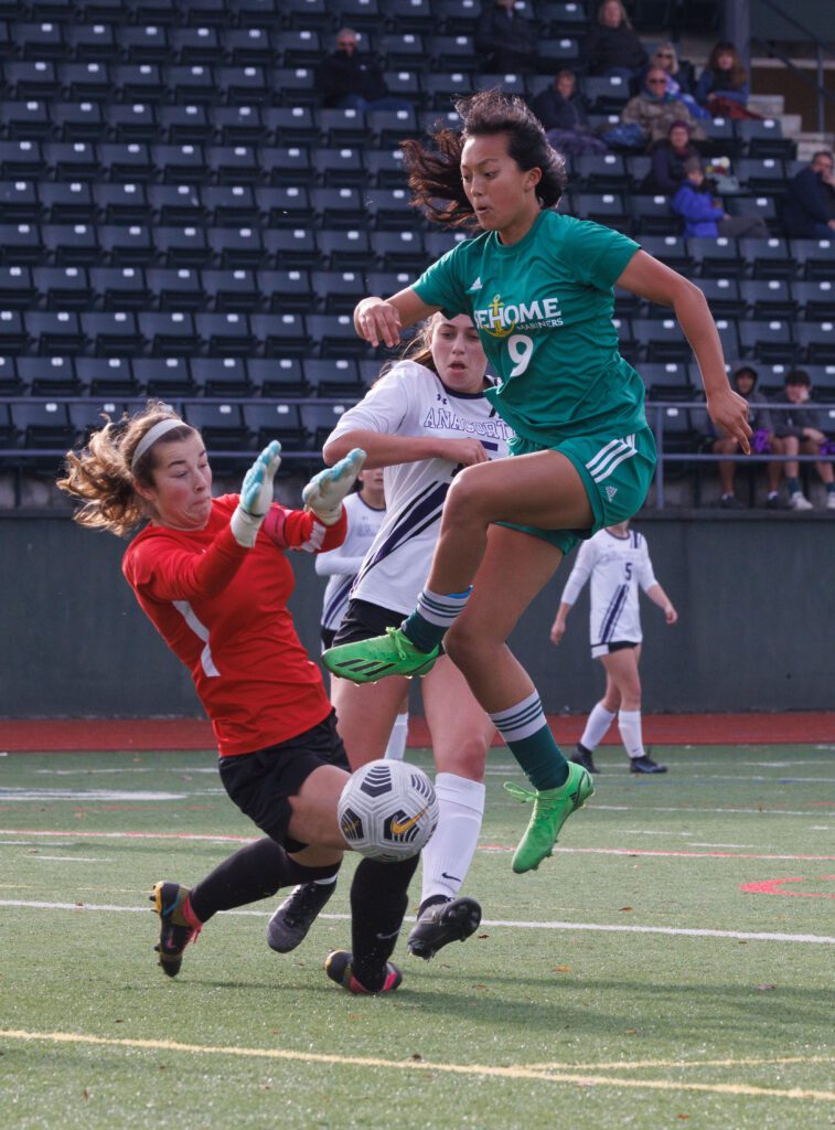 Sehome’s Evelyn Keay leaps for the shot but gets blocked by Anacortes goalkeeper Claire Schnabel who is bracing with both hands.