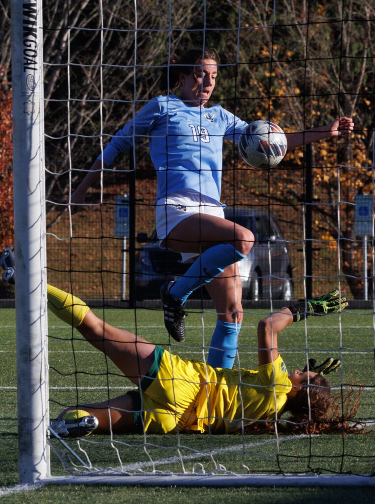 Stepping over the goalie and into the net, Western Washington University’s Tera Ziemer uses her stomach to bump the ball into the goal as the goalie braces for impact below her.