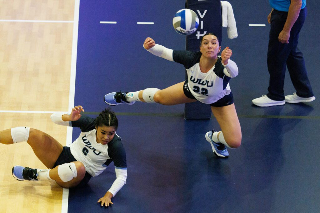 Western Washington University's Gabby Gunterman dives around teammate Malia Aleaga who has fallen to the gym floor.