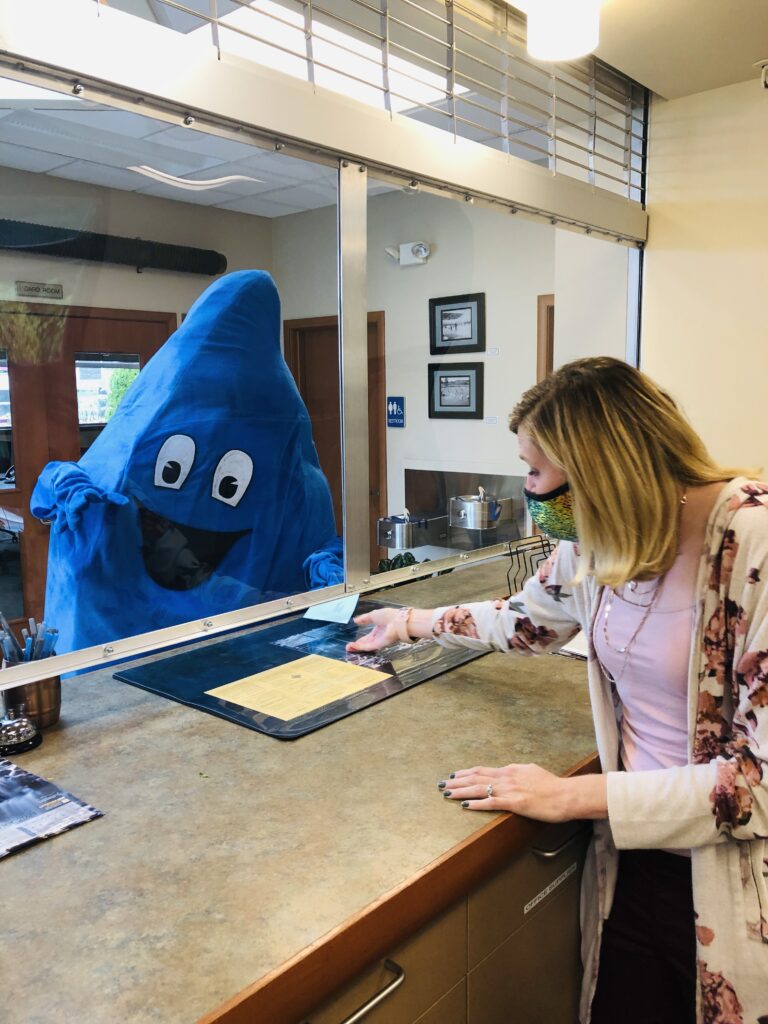 Wayne, the Water Week event mascot, hands over paper to a clerk.