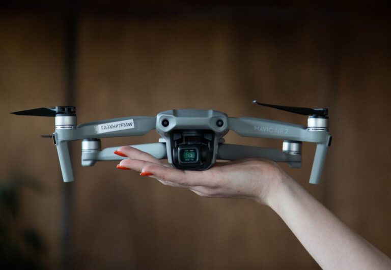 A person holds up a drone with one hand.