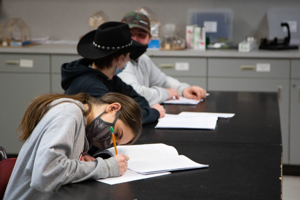 Seventh graders do school work while wearing a mask.