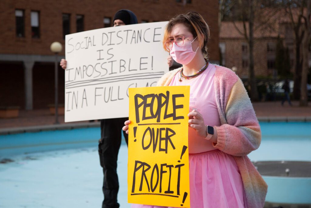 Astrid Ervin holds up a bright yellow sign next to another protestor.