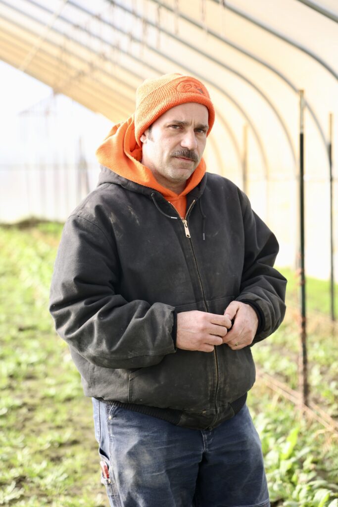 Skuter Fontaine stands inside a greenhouse.