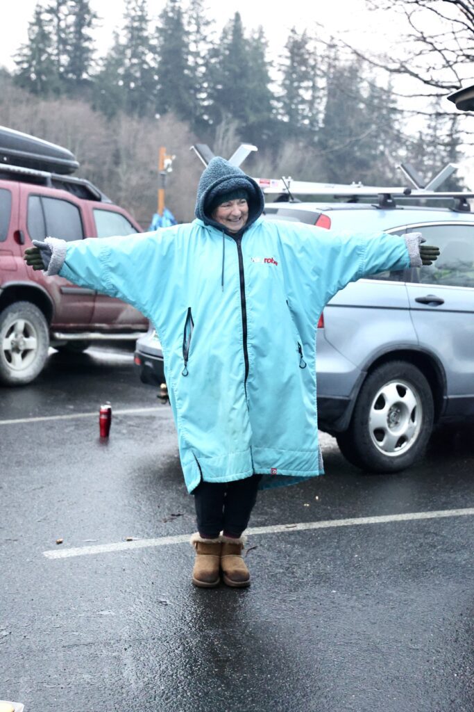 Kelcey Bates stands with arms outstretched while wearing warm clothes.