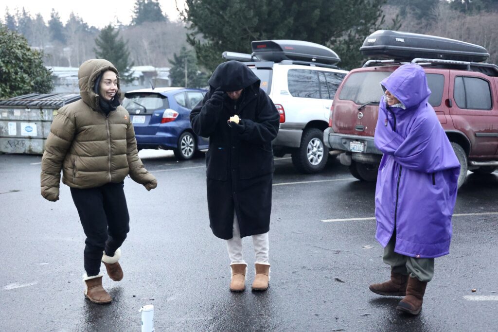 From left, Blaik Kessinger, Kim Brown and Olivia Gleser chat while they warm up with thick coats.