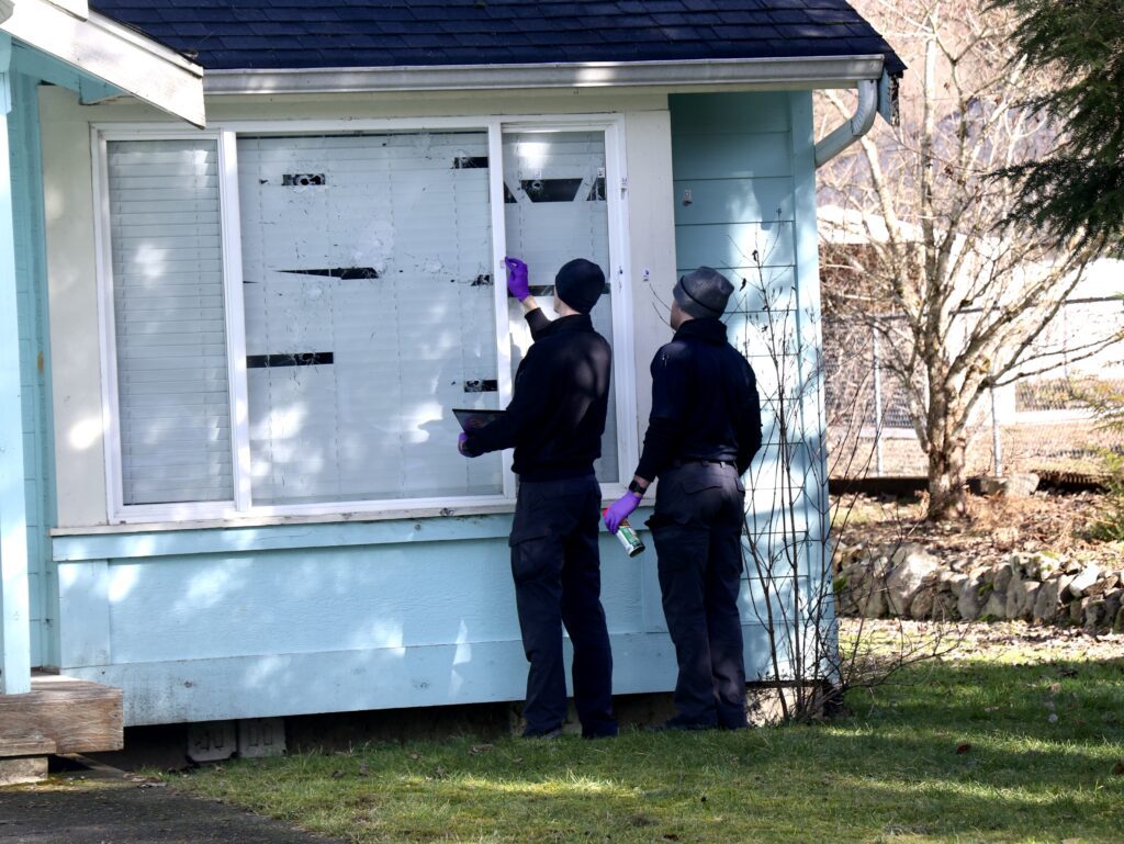 Officers mark bullet holes in the window of Joel Young's house.