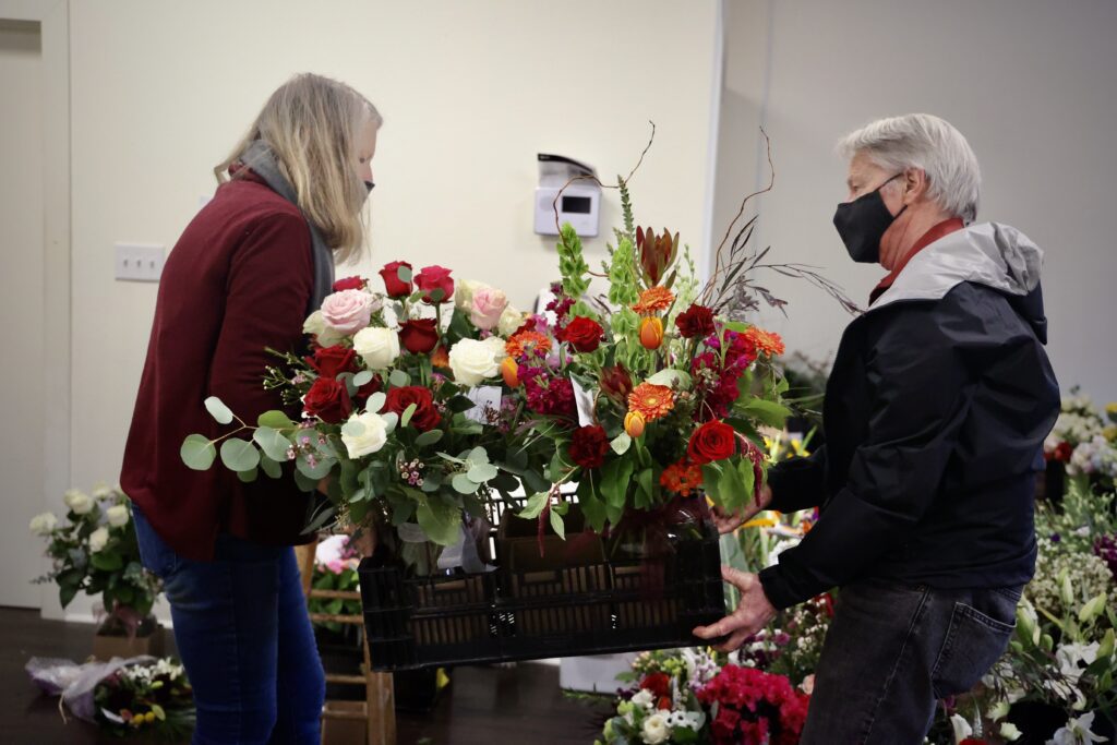 Trish Manley, left, and Steve Blair carefully transport a load of bouquets in crates.