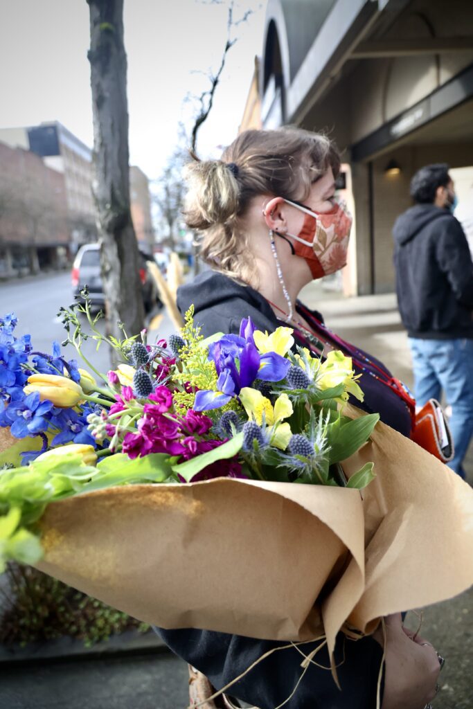 Nicola Thompson, a regular at the flower shop, holds the custom-made bouquet with one arm.