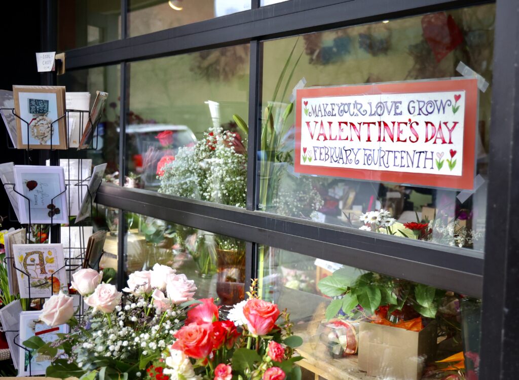 A sign is taped on the store window with a valentines theme.