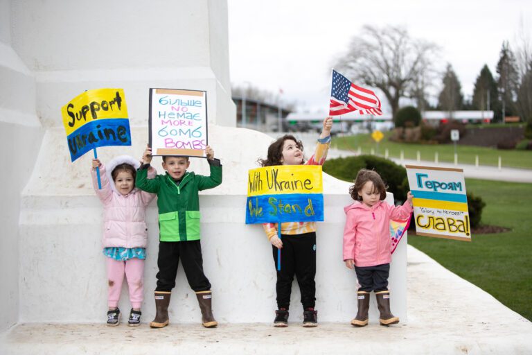 Ukrainian-American children stand on the Peace Arch with various signs of support for Ukraine.