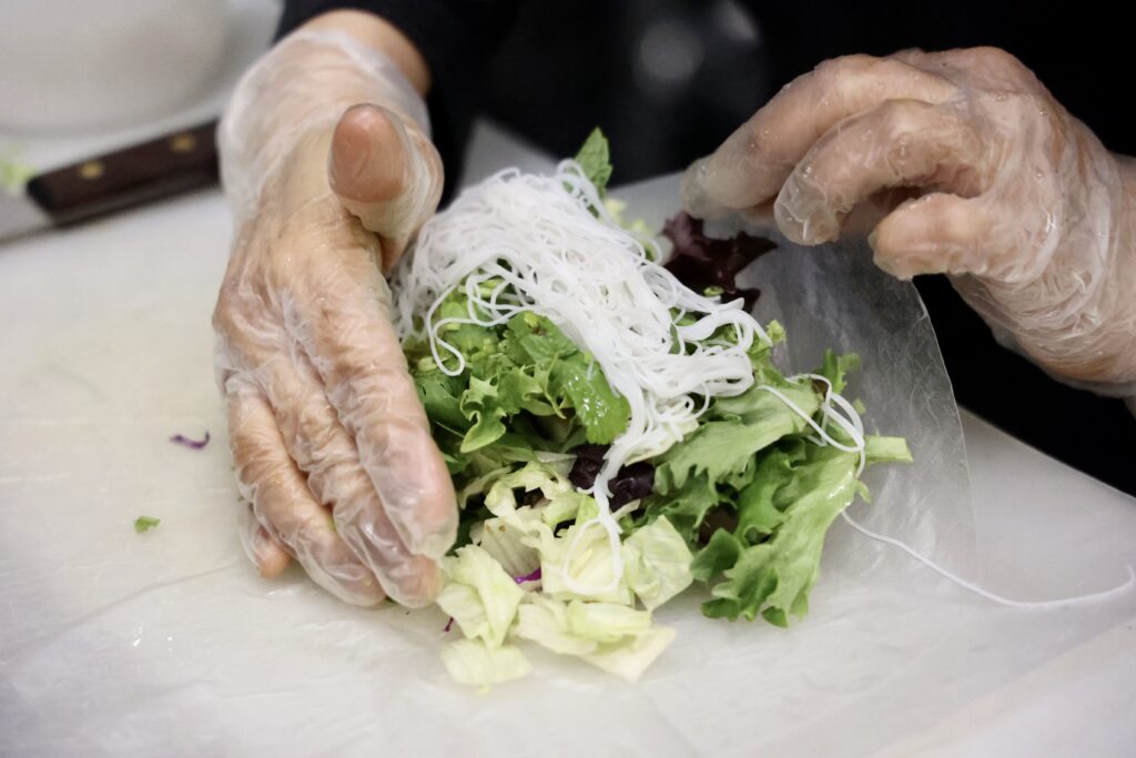 Sous-chef Naphada Ngoenjan rolls fresh vegetables and noodles in rice paper to make a fresh roll dish.