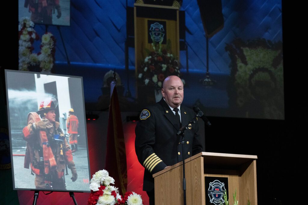 Fire Chief Larry Hoffman spoke at Crosswhite’s celebration of life next to a picture of Dean Crosswhite.