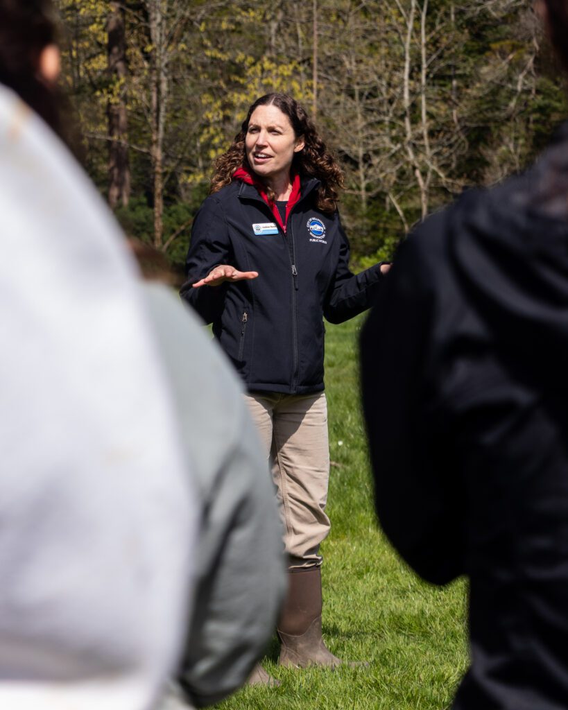 Analiese Burns, habitat and restoration manager for the city of Bellingham, speaks to volunteers as she gestures with both hands.