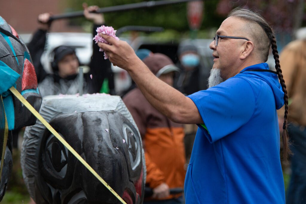 Frederick Lane spreads fallen flower petals on the totem.