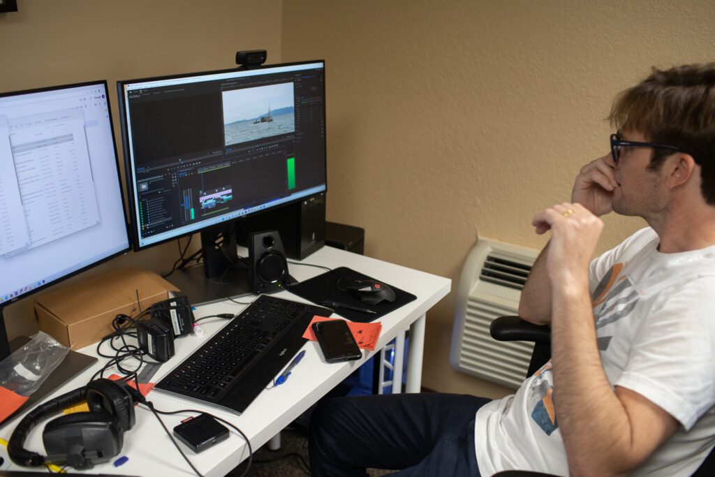 Producer Jordan Riber edits clips of the Salmon People Project with double monitors.